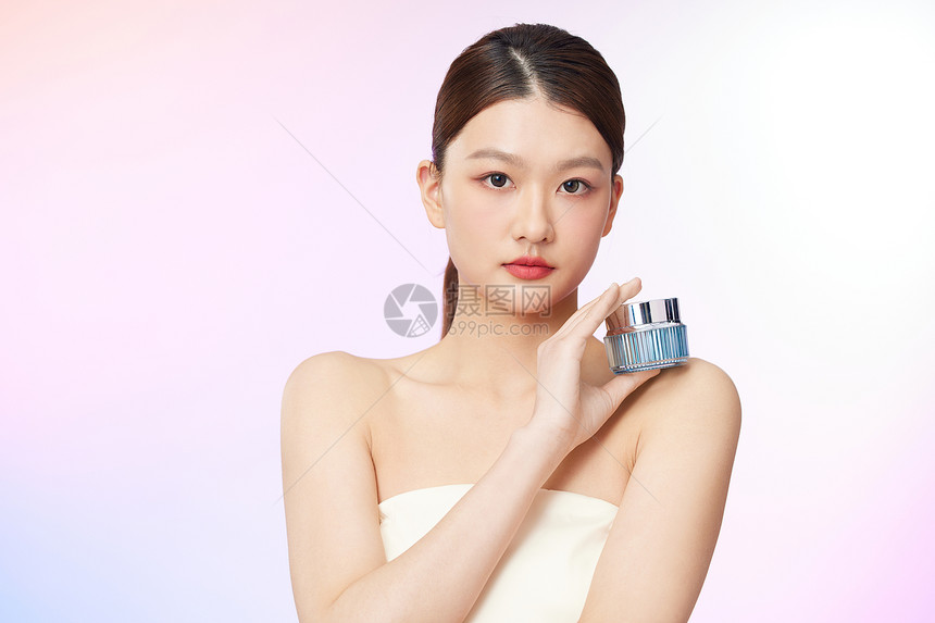 手持化妆品放在肩部展示的年轻美女图片