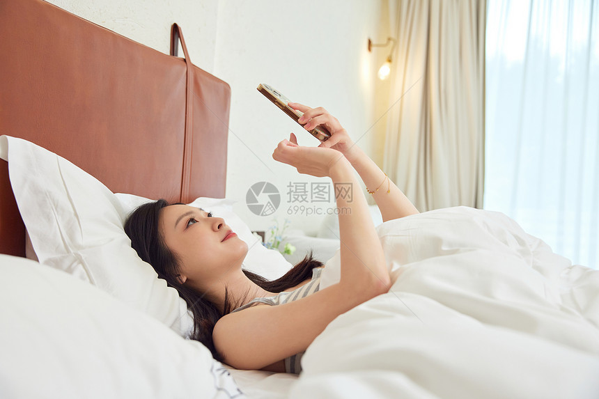 在床上刷手机的女生图片