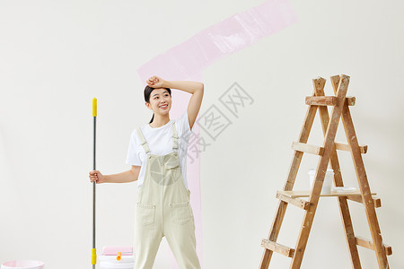 努力粉刷墙面的女性擦汗图片