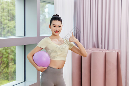 运动女生抱着瑜伽球点赞高清图片