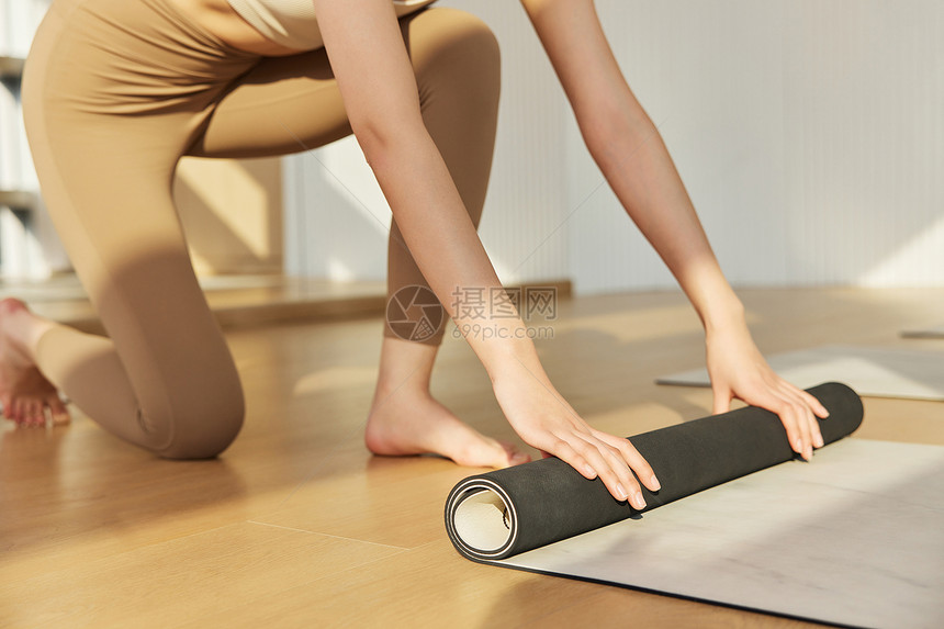 室内瑜伽运动女生卷瑜伽垫特写图片