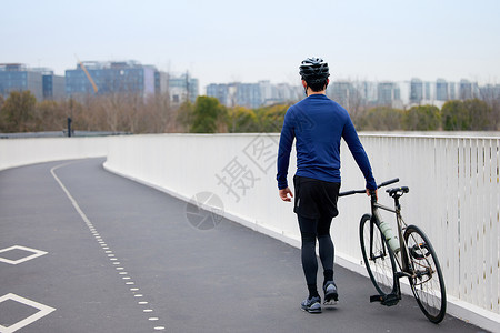 推着自行车行走的男性背影背景图片