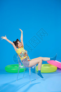 蓝色背景夏日美女坐在椅子上高清图片