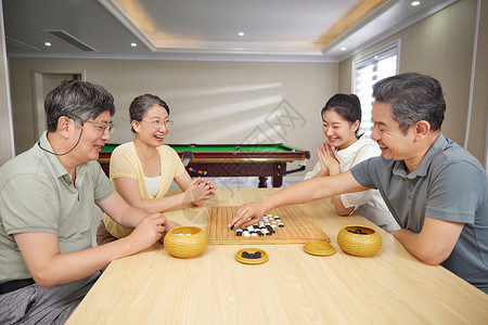 休息的女人护工陪同老人在活动室下棋背景