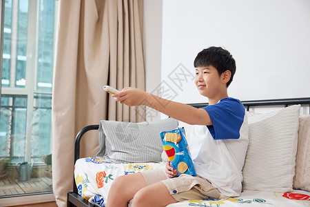 沉迷电子游戏男孩拿着薯片看电视背景