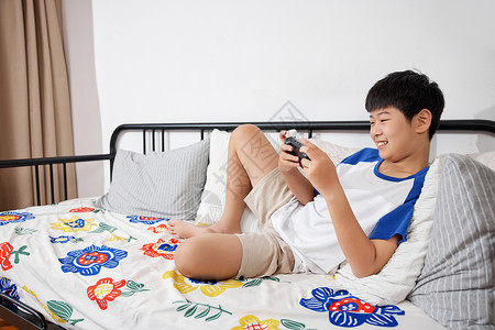 沉迷电子游戏开心地在沙发上玩手机的男孩背景