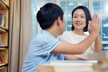 读书男孩妈妈在书房开心地与孩子击掌背景