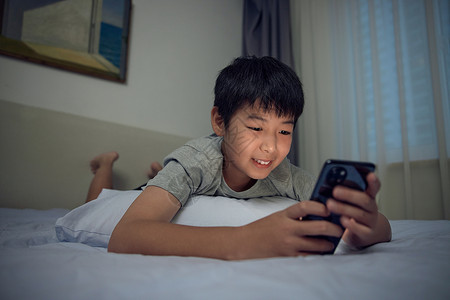 男孩在床上开心地熬夜玩手机图片