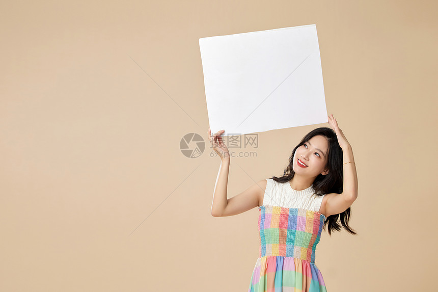 双手高举白板的年轻女性图片