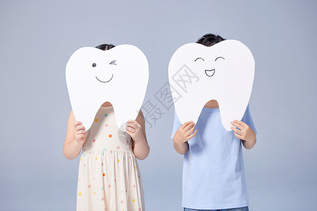 儿童品牌店模型两个小朋友用牙齿模型手举牌挡住脸背景