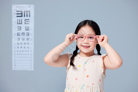 上新促销标签小女孩在视力表前戴上新眼镜背景