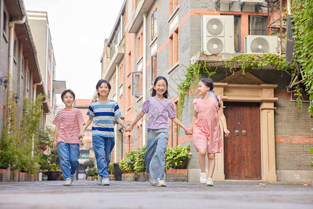 大街上女孩四个小朋友手牵手快乐地在大街上玩耍背景