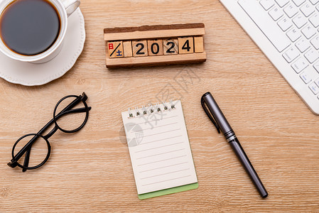 2024年龙年大吉木板桌上的笔记本眼镜框背景