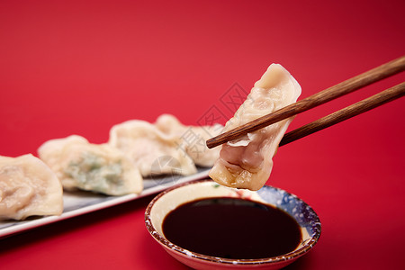 红色背景筷子夹起水饺蘸醋特写背景图片