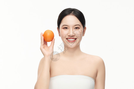 穿着抹胸的女人举着一个橙子拍照高清图片