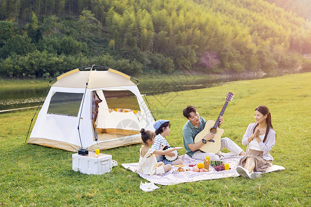 一家人坐在草地上露营背景