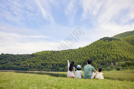 户外孩子一家四口坐在草地上的背影背景