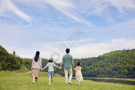 一家郊游一家四口站在草地上快乐的散步背景