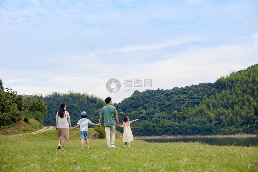 幸福的一家人在草原上手拉手散步图片