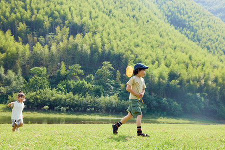 亲子玩户外露营两个孩子在玩草坪上奔跑背景