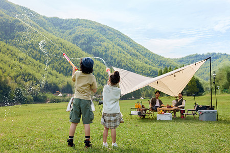 夏天露营户外露营两个孩子在玩水枪背景