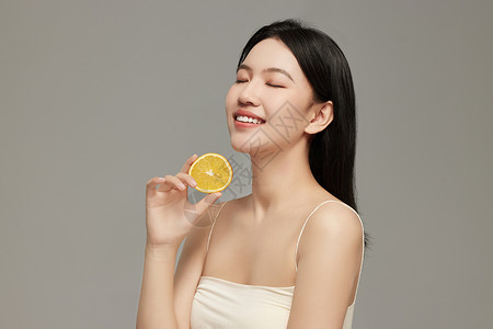 美容水果手上拿着橙子片自信展示皮肤状态的气质美女背景