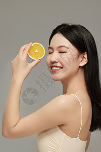 水果女人手里拿着橙子片的侧颜模特照背景