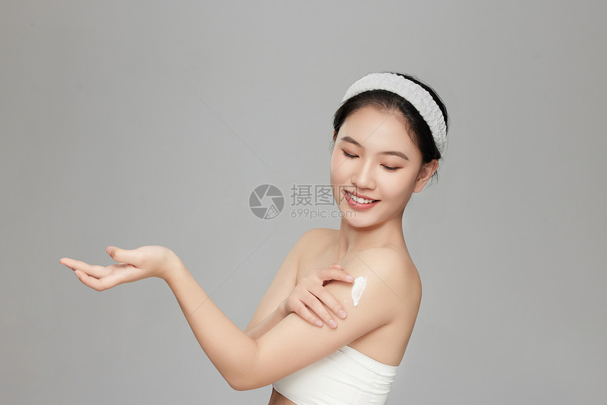 微笑展示手臂上身体乳的年轻女孩图片