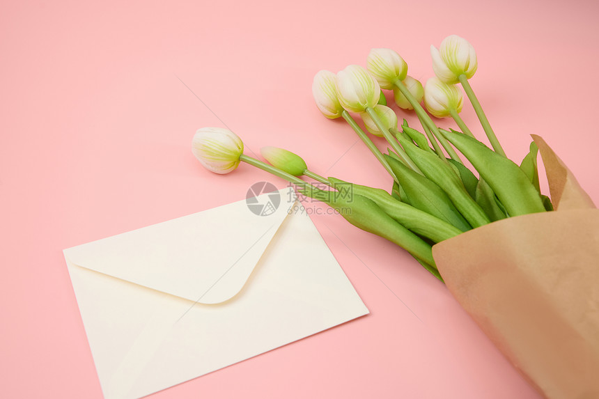 粉色桌面上的白色信封和郁金香图片