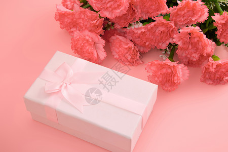 一大束娇艳欲滴的红色康乃馨和粉色蝴蝶结礼物盒高清图片