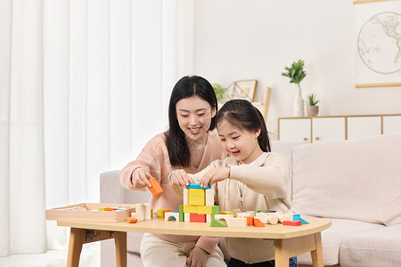 母亲和孩子年轻妈妈正和女儿一起堆积木玩耍背景