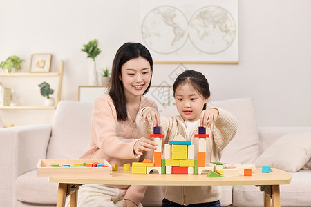 母女一起出门年轻妈妈正和女儿一起堆积木玩耍背景