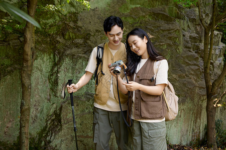 轻松拿证徒步旅行的年轻情侣拿相机拍摄背景