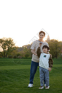 带墨镜的父子爸爸带着儿子在草坪上玩飞机玩具背景