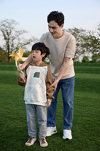 带孩子玩的父亲爸爸带着儿子在草坪上玩风车背景