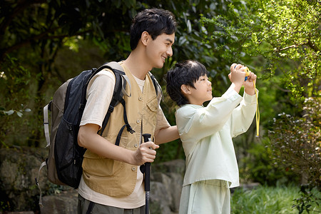 年轻帅气小男孩用相机拍山景背景