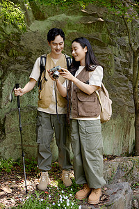 背包去旅行漂亮女孩给男朋友看相机里拍的山上景色背景