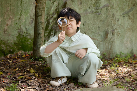 童年有趣小男孩拿着放大镜在植物园摆拍背景