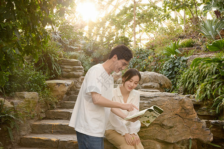年轻情侣在植物园里看书高清图片