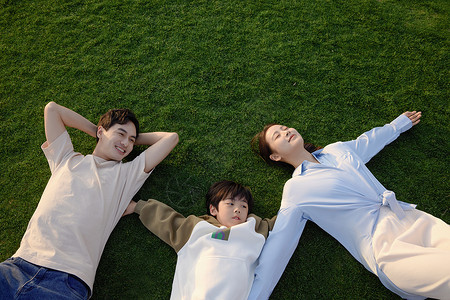 一家三口插画周末躺在草坪上放松的一家三口背景