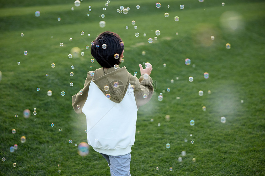 在草坪上玩泡泡的小男孩图片