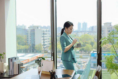 上班的女性商务女性站在落地窗前喝咖啡背景