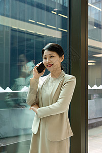 大厦走廊女白领在公司大楼走廊拿着手机打电话背景