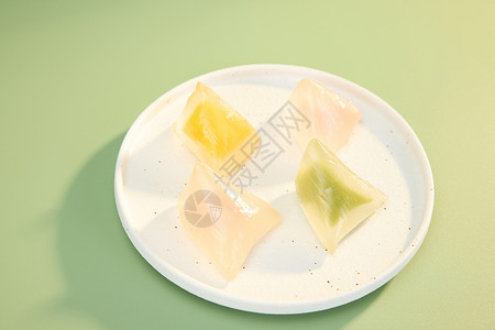 彩色餐具绿色背景下盘中彩色水晶粽子背景