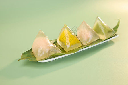 彩色餐具盘中粽叶上的彩色水晶粽子侧视图背景