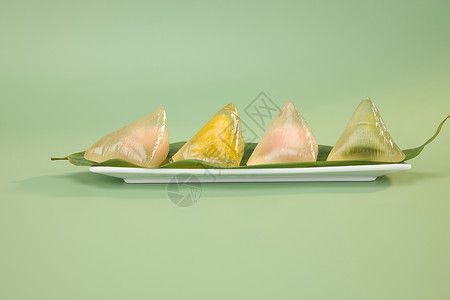 四个粽子划龙舟盘中粽叶上的四个彩色水晶粽子背景