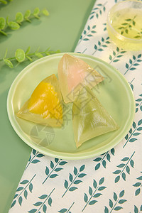 传统餐饮绿色圆盘上的三个水晶粽子背景