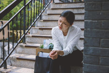 被裁员的女职员坐在楼梯上伤心开除高清图片素材