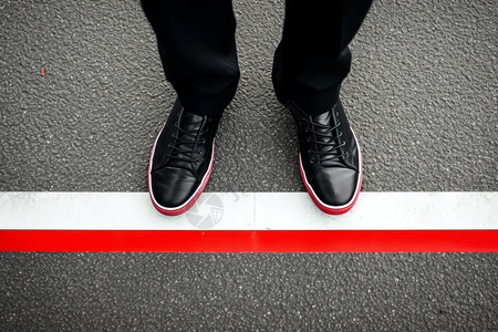 黑色鞋子站在红白线上高清图片