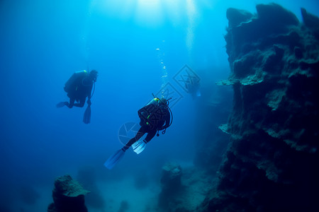深度潜水员们在附近的岩石结构附近游泳背景